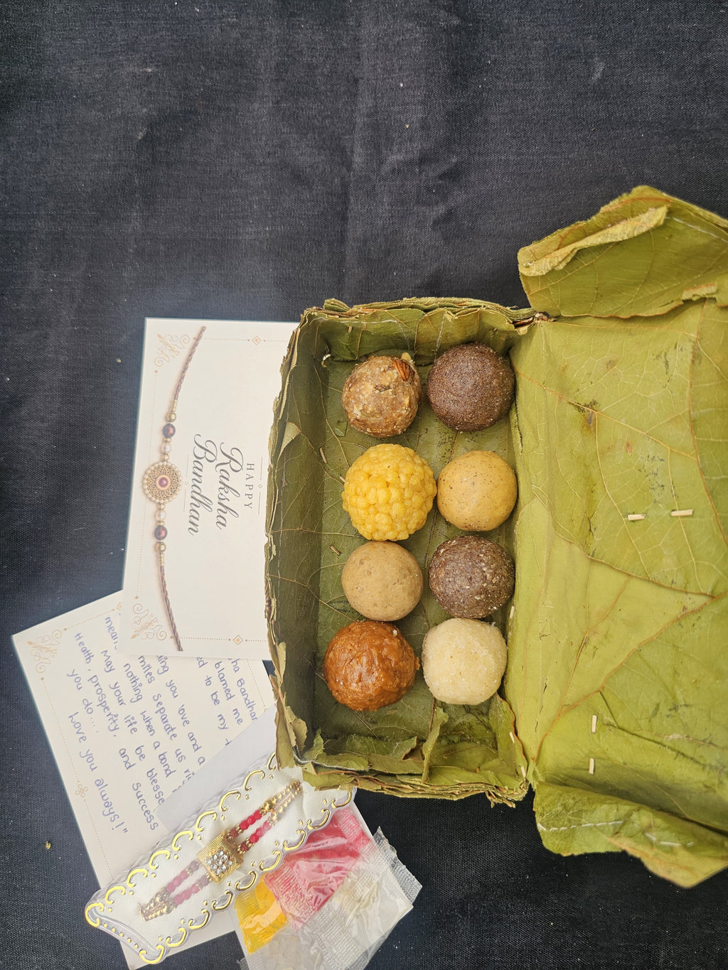 "Rakhi Mega Combo hamper with handmade laddus and festive snacks"
"8 assorted traditional laddus in handmade leaf box"
"Premium rakhi with kumkum and puja essentials"
"Beautifully packaged Rakhi gift hamper ready to send"
"Festive snacks and handmade sweets Rakhi combo"